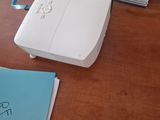 a small projector sitting on a desk next to a pile of books