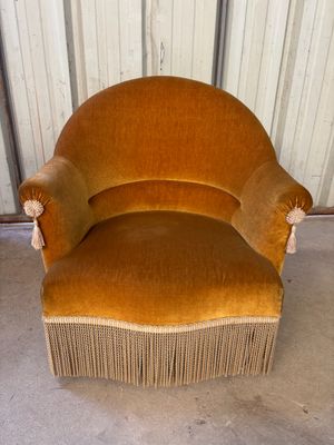 une chaise marron ornée de franges, placée devant un mur