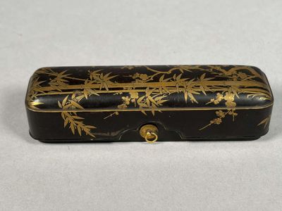 a small black and gold box with gold flowers on it