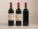 trois bouteilles de vin rouge sont posées les unes à côté des autres sur une surface blanche