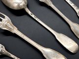 four silver spoons and two silver spoons on a black surface