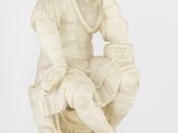 une statue en marbre blanc représentant un homme assis sur une chaise