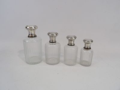 quatre petites bouteilles en verre avec des bouchons argentés et un bouchon en argent