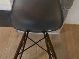 black eames chair with wooden legs on wooden floor next to a wall