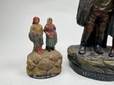 two figurines of a man and a woman standing on a rock