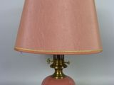 lampe en verre rose avec des finitions dorées et un abat-jour, sur fond blanc
