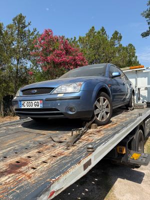 a blue car on the back of a flatbed tow truck