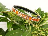 a bracelet that says seller on it sitting on a plant