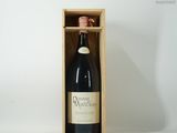 une bouteille de vin dans un coffret en bois posée sur une surface blanche