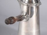 a silver coffee pot with a wooden handle on a table
