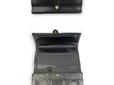 un portefeuille en cuir noir comportant deux compartiments et muni d'un fermoir doré
