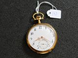 une montre de poche en or posée sur une surface noire, avec une étiquette de prix