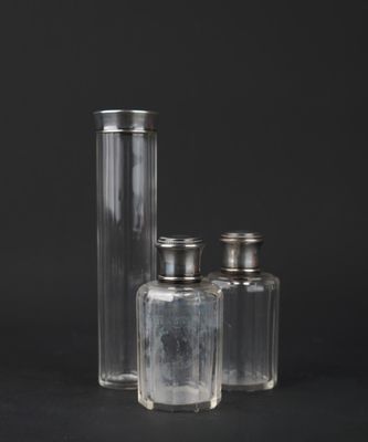 three clear glass bottles with silver lids on a black background