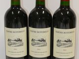 three bottles of red wine are lined up on a table