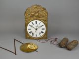 une horloge dorée avec des chiffres romains, à côté de deux aiguilles