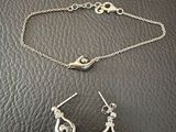 a close up of a silver bracelet and earrings on a black surface