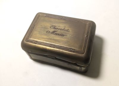 une vieille boîte en métal portant une inscription, posée sur une table