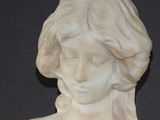 marble bust of a woman with long hair and a flower in her hair
