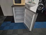 a small refrigerator with a sink and a microwave on the counter
