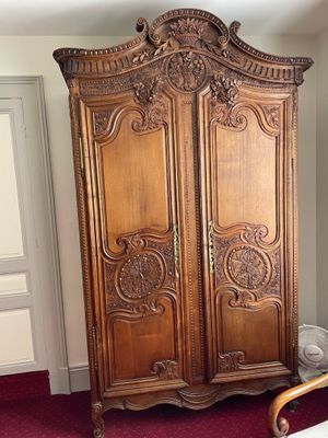 a wooden armoire in the corner of a room