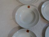 six assiettes blanches vides sont disposées en cercle sur une table