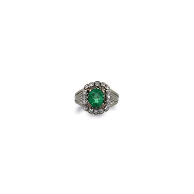 gros plan d'une bague avec une pierre verte entourée de diamants