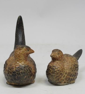 une paire d'oiseaux en céramique posés l'un sur l'autre sur une surface blanche