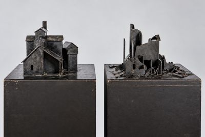 une paire de sculptures métalliques représentant des bâtiments et un cheval dans un champ