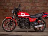 a red and black motorcycle parked in front of a brick wall