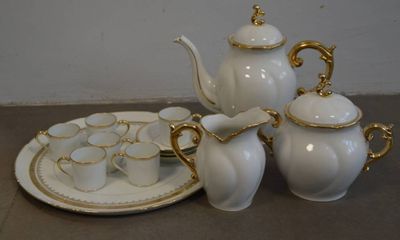 un service à thé blanc orné de motifs dorés, posé sur une table