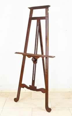 a wooden easel on a tile floor with a white wall in the background