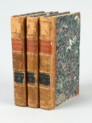 trois vieux livres posés l'un sur l'autre sur une surface blanche