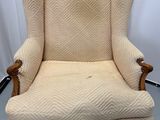La chaise est en bois et son assise est rembourrée de couleur beige.
