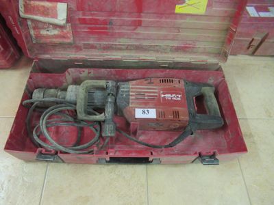 une boîte à outils rouge posée par terre, contenant une perceuse