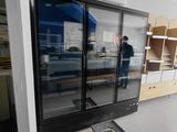 un homme qui se tient debout dans une pièce dont la porte est en verre