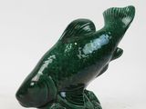 a green fish figurine sitting on top of a table