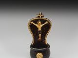 une figurine noire et dorée sur laquelle est représenté un crucifix