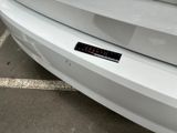 a sticker on the bumper of a white car that is parked in a parking lot