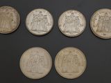 six different types of silver coins on a black surface