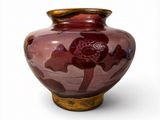 un vase rouge orné d'une fleur, posé sur une surface blanche