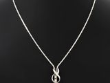 un collier en argent avec un nœud et une chaîne, posé sur un mannequin