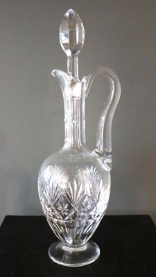 un vase en verre transparent muni d'une anse, posé sur une table noire