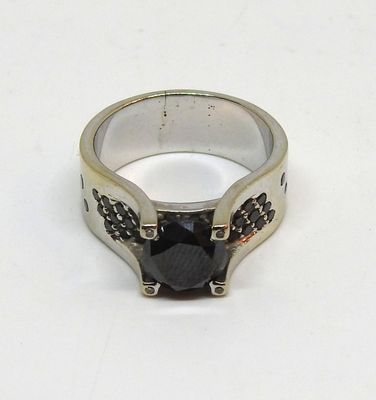 bague en argent sertie d'une pierre noire sur un fond blanc