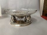 a glass bowl on a silver plate on a table