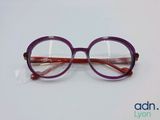 des lunettes violettes posées sur une surface blanche, sur fond bleu