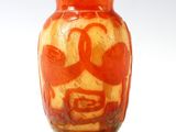 un vase orange orné d'un visage, posé sur une table