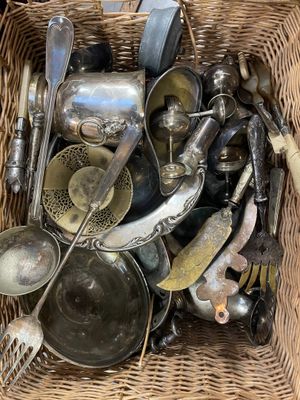 un panier en osier rempli de vieux couverts et ustensiles en argent