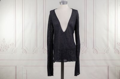 une robe noire posée sur un mannequin devant un mur blanc