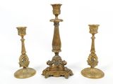 three antique brass candlesticks on a white surface with a white background