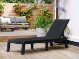 a black chaise lounger on a wooden deck